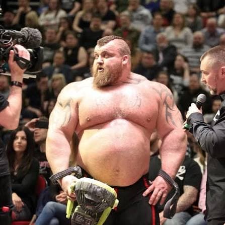 A strongman holding a trophy at a competition